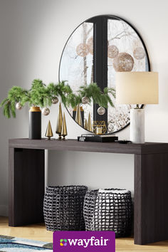 a console table with plants and vases on it in front of a round mirror