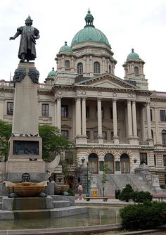 a large building with a fountain in front of it and a statue on the outside