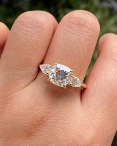 a woman's hand with a three stone ring on top of her finger,