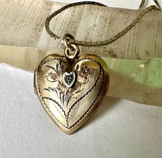 "a lovely old gold fill heart locket necklace.  there is a tiny clear stone set within a white gold heart which i believe is a diamond chip but too small to test with my tester.  beautiful engravings on the face including flowers.  i have popped out the man's photo to see the markings on the inside:  1/20 12KGF on sterling, and A.L.L. Co.  A google search lead me to A. L. Llndroth, a company that existed from 1922 to 1950.  locket has light wear, closes nicely, and is truly beautiful.  the chain is something that someone added later, a sterling box chain. height of pendant:  15/16\" height of heart:  13.16\" width of heart:  3/4\" length of chain:  18\"" Old Locket Necklace, Vintage Charm Heart Pendant Necklace For Anniversary, Anniversary Necklace With Vintage Charm And Heart Pendant, Vintage Charm Heart Pendant Jewelry For Mother's Day, Mother's Day Vintage Heart Pendant Jewelry, Victorian Jewelry In 14k Gold With Hallmark, Heirloom Oval Jewelry For Valentine's Day, Victorian 14k Gold Jewelry With Hallmark, Victorian Gold Jewelry For Anniversary Gift