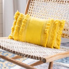 a yellow pillow sitting on top of a wicker chair