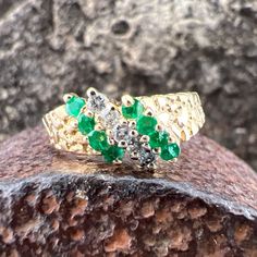 Gorgeous Emeralds accented by Diamonds and set in a 14k Yellow Gold Ring. US Size 6 1/2 Emeralds 0.32 ctw, approximately  Diamonds 0.1 ctw, approximately  Widest point measures approximately 7.5 mm Tapers down to approximately 1.9mm at the back of the shank Weighs approximately 2.8 grams. Stamped 14K Green Diamond Multi-stone Birthstone Ring, Green Diamond Birthstone Ring With Multi-stone, Green Multi-stone Diamond Ring, Heirloom Cubic Zirconia Multi-stone Diamond Ring, Yellow Gold Multi-stone Emerald Cut Diamond Ring, Green Diamond Cut Diamond Ring, Yellow Gold Diamond Cluster Ring With Multi-stone, Diamond Cluster Ring With Brilliant Cut For May Birthstone, Anniversary Yellow Gold Multi-stone Emerald Ring