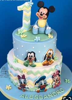 a mickey mouse birthday cake with the number one on top and other characters around it