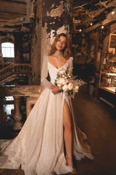 a woman in a white dress standing next to a tree with her legs slited