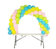 an arch made out of balloons on top of a white table with a bench underneath it