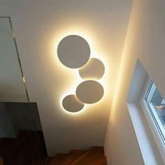 the light is shining on the wall above the stairs and below it are three circles