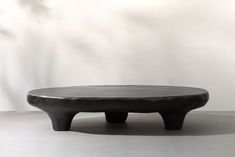 a black coffee table sitting on top of a white floor next to a planter