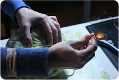 two hands are holding something while sitting at a table