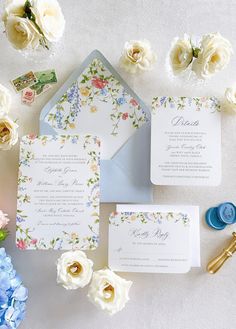 the wedding stationery is laid out on top of the table with flowers and cards