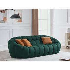 a green couch sitting on top of a white rug in a living room next to a lamp