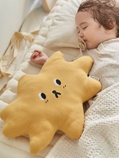 a baby sleeping on top of a bed next to a stuffed animal pillow with eyes