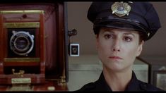 a woman in police uniform holding up an old fashioned radio and looking at the camera