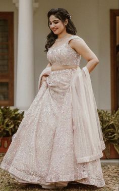 a woman in a pink and white gown posing for the camera with her hands on her hips