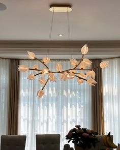 a chandelier hanging over a dining room table with chairs and vases on it