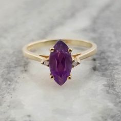 This is a stunning purple marquise cut Amethyst set in a yellow gold ring. There's a 1.3mm diamond set on each side to add a little more sparkle. Perfect for someone who loves Amethyst or has a February birthday! It is a US size 6 and it could be resized by your local jeweler The gemstone measures 3/16 inch (5mm) wide 3/8 inch (10mm) tall It is marked '10kp CTR' on the inside of the band. KP stands for Karats Plumb The ring weighs 1.6 grams. The ring is in good vintage condition, it does show so Gold Marquise Amethyst Ring, Yellow Gold Marquise Amethyst Ring As Gift, 14k Gold Marquise Amethyst Ring Fine Jewelry, Gold Marquise Amethyst Ring In 14k, Vintage Multi-stone Amethyst Ring In 14k Gold, Ctr Rings, Amethyst Set, Amethyst And Diamond Ring, February Birthday