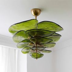 a green chandelier hanging from the ceiling in a room with white walls and windows