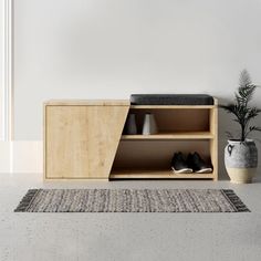 a wooden cabinet sitting next to a potted plant on top of a white rug