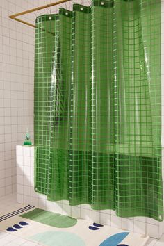 a green shower curtain in a bathroom with blue and white tiles on the floor next to it