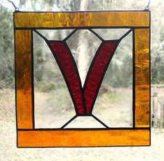 a stained glass window with the letter v in it's center, hanging from a chain