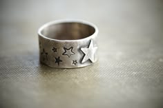 "All sorts of stars adorn this wide band. Three different styles of stars are stamped all the way around the ring with one star cutout in the center. The band measures about 3/8\". I gave it a more rustic aged look so there is texture from hammering and forming. I blackened the surface and polished it back up so all the layers and textures would be accented. Made in sterling silver. CURRENT LEAD TIME ON ALL ORDERS: 2 Weeks SHIP TIME TO US: 2-7 business days SHIP TIME OUTSIDE US: Up to 8 weeks (a Etched Silver Ring, Soldering Rings, Jewelry Links, Wide Silver Band, Metal Jewelry Making, Simple Silver Jewelry, Dope Jewelry, Funky Jewelry, Star Ring