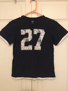 Gymboree Boys Navy Blue Sports Number 27 Layered Look T-shirt Jersey Sz 7 EUC. Condition is "Pre-owned". Shipped with USPS First Class. Navy blue with distressed white screen printed number 27. Decorative green stitching outlines the numbers. Shirt has a layered distressed look around the edges. Preowned in excellent condition. Minimal wash wear. Casual Sports T-shirt With Number Print, Blue Crew Neck T-shirt With Number Print, Casual Blue Tops With Number Print, Cotton Tops With Number Print For Sports Season, Short Sleeve Tops With Number Print For Sports Season, Navy Blue Graphic Tee, Sports Numbers, Number 27, White Screen