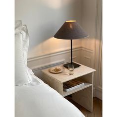 a table with a lamp on it next to a bed