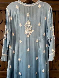 This Blue Ombre Muslin Silk Handcrafted Lucknowi Chikankari A Line Kurta Long Dress is a stunning piece of art. The beautiful blue shade dress is perfect for any special occasion. The luxurious fabric and intricate Lucknowi Chikankari embroidery make it a timeless piece that will never go out of style. Length 48" inches Long sleeves 18" inches Round neck A line Muslin silk Chikankari work Hand embroidered Dry Clean Fit: True to sizeInside Margin: NoTouch and Feel: Soft and ComfortableDispatched Transitional Blue Salwar Kameez With Floral Embroidery, Indigo Kurta With Chikankari Embroidery For Festivals, Indigo Traditional Wear With Chikankari Embroidery And Long Sleeves, Traditional Indigo Kurta With Chikankari Embroidery, Blue Traditional Drape Kurta For Summer, Summer Dress With Chikankari Embroidery In Chanderi, Blue Chanderi Dresses With Cutdana, Transitional Blue Salwar Kameez With Chikankari Embroidery, Chanderi Tunic Dress With Resham Embroidery