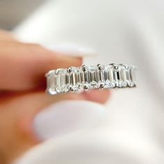 a woman's hand holding a diamond ring with three baguetts on it