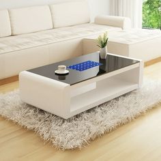 a living room with a white couch, coffee table and potted plant in it