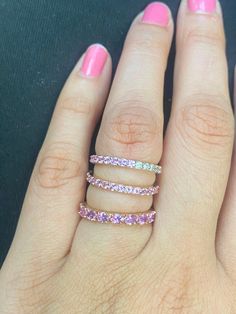 a woman's hand with pink and white stones on it, wearing a ring