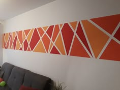 an orange and white wall in the corner of a room with a gray couch next to it