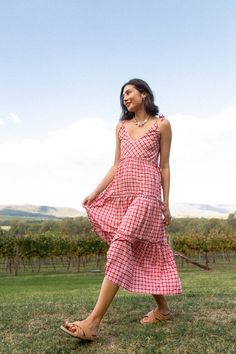 Feel alive in the airy Viviana; a multiway midi dress to stand the test of time and complete your capsule wardrobe. Dainty yet playful, alluring yet striking. A pink gingham staple piece taking your sun dress to new heights with its multifunctional and practical design and fun, feminine print. Sway into any occasion with considered lightweight fabric made for the warmer temperature or team with boots and a light-weight knit for the cooler seasons. 
 Thoughtfully crafted to be customisable and wo Spring Breezy Ruched Midi Dress, Breezy Spring Midi Dress With Ruched Detail, Flowy Midi Sundress With Tie Straps, Flowy Midi Dress With Tie Straps For Brunch, Flowy Midi Dress With Tie Straps For Garden Party, Elegant V-neck Dresses For Picnic, Elegant V-neck Dresses For Picnics, Ruched Maxi Length Midi Dress For Garden Party, Ruched Midi Length Sundress For Garden Party