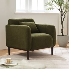 a green chair sitting on top of a white rug next to a potted plant