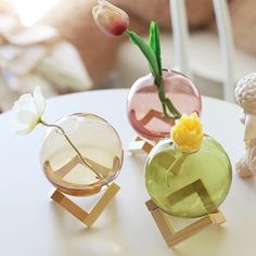 three vases with flowers in them sitting on a table next to a teddy bear