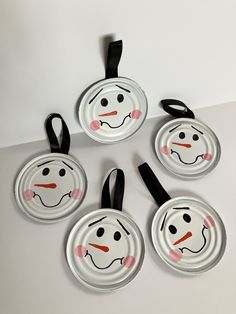 four paper plates with faces painted on them are arranged in the shape of a snowman