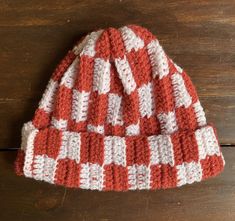 a red and white knitted hat sitting on top of a wooden table