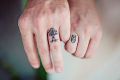 two fingers with tattoos on them, one has an owl and the other has a tree