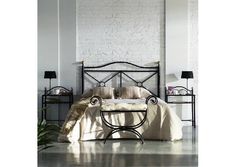 a bedroom with white brick walls and black iron bed frame, along with two side tables