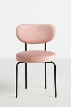 a pink chair sitting on top of a white floor next to a black metal frame