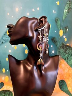 This enchanting mermaid moon ear cuff is sure to make a statement and bring out your inner magic! Silver ear cuff is embellished with a charm of two women in the moon, rainbow mermaid tail charm, iridescent drop crystals, seashell and starfish, and electroplated lava stone beads all dangling from silver and rainbow chains. This ear cuff is perfect for adorning pierced and non-pierced ears, and is lightweight and comfortable to wear. Lava Stone offers the following positive energies for the weare Whimsical Moon Charm Dangle Jewelry, Silver Bohemian Cartilage Earrings For Party, Whimsical Dangle Moon Charm Jewelry, Bohemian Ear Cuff For Party, Whimsical Dangle Jewelry With Moon Charm, Bohemian Style Pierced Ear Cuff For Party, Whimsical Dangle Jewelry For Festivals, Fantasy Festival Dangle Earrings, Fantasy Dangle Earrings For Festival