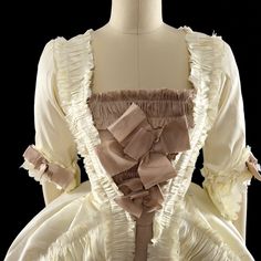 A Rococo Style gown made from polyester dupioni. The gown features an abundance of ruffles, made from the same fabric as the gown and strategically placed to add volume and movement to the dress. The separate underskirt is also decorated with ruffles and will provide additional volume and texture to the overall look of the gown. The sack back drapes elegantly over the back and hips and creates a soft, flowing silhouette.This dress can be made in many different color combinations. The front of th Rococo Style Ruffled Formal Dress, Formal Rococo Dress With Ruffles, Rococo Style Ball Gown With Ruffles, Rococo Ball Gown With Ruffles, Fitted Marie Antoinette Dress With Ruffles, Marie Antoinette Style Fitted Dress With Ruffles, Satin Dresses With Ruffles And Voluminous Skirt, Marie Antoinette Style Victorian Dress With Ruffles, Regency Victorian Dress With Ruffles In Cream