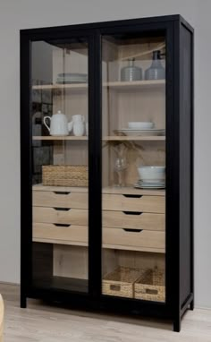 a black cabinet with glass doors and wicker baskets