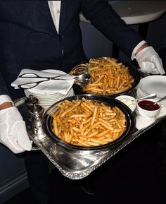 two trays filled with french fries on top of a table