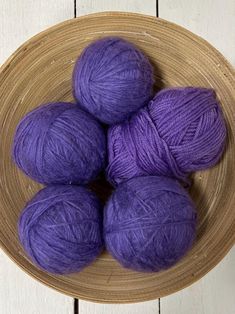 four balls of purple yarn in a bowl