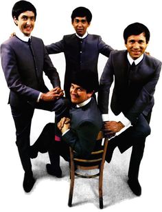 four men in suits and ties posing for a photo with one man sitting on a chair