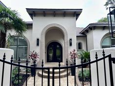 a white house with black iron fence and palm trees