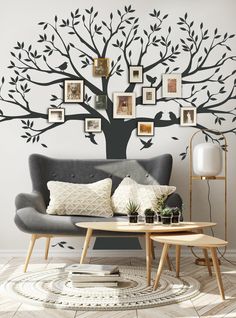 a living room with a tree wall decal on the wall and pictures above it