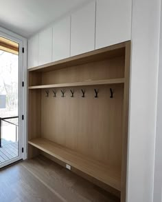 an empty room with wooden shelves and white doors, looking out onto the deck area