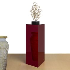 two vases sitting next to each other on a wooden table in front of a white wall