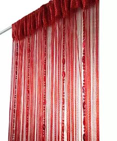 red and white curtain hanging on the side of a wall with beads attached to it